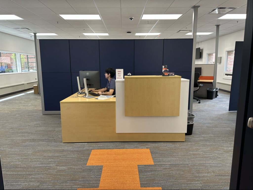 Welcoming students in with the front desk and the block orange I on the ground.
