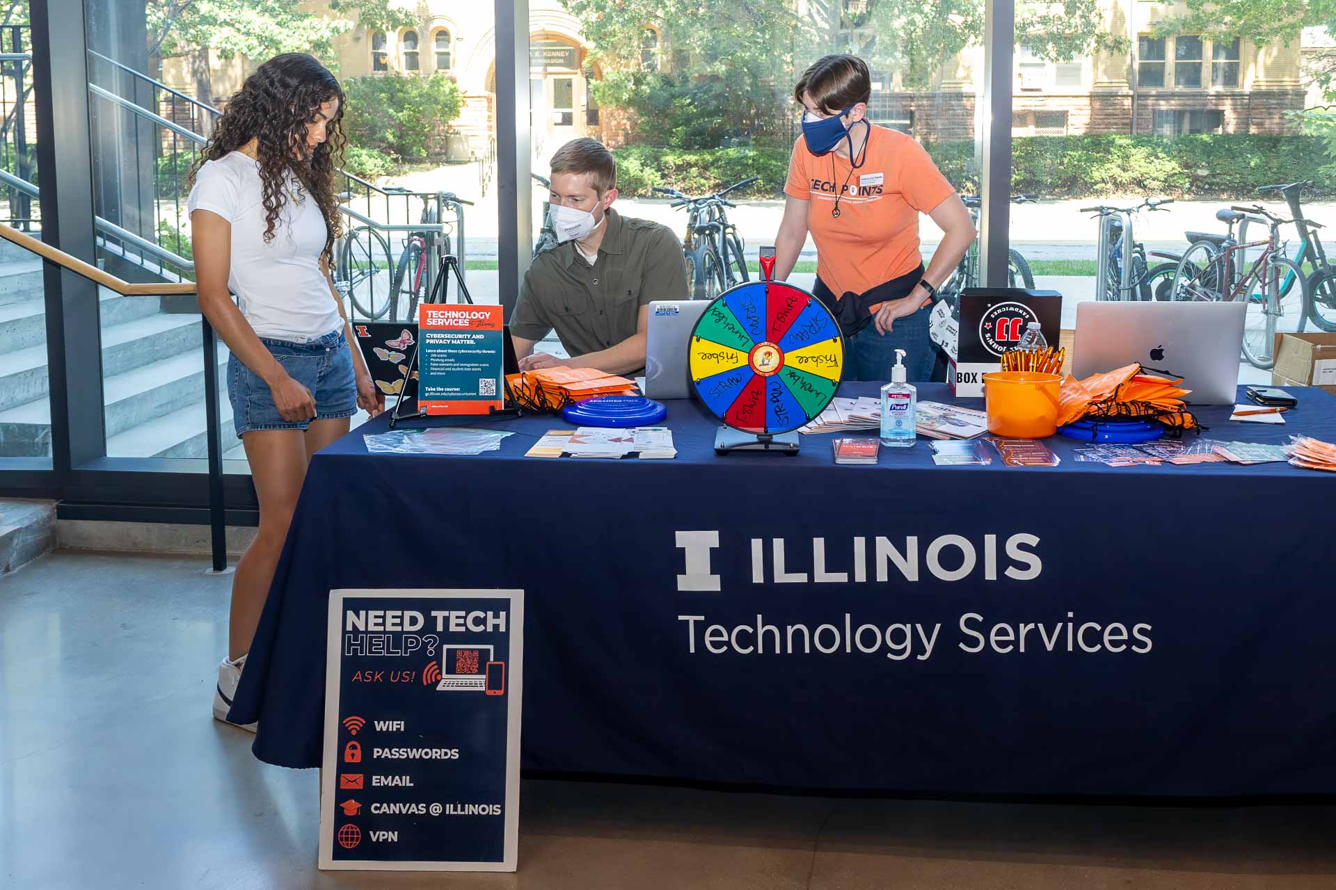 Tech Points table with two volunteers helping a student inside CIF. 