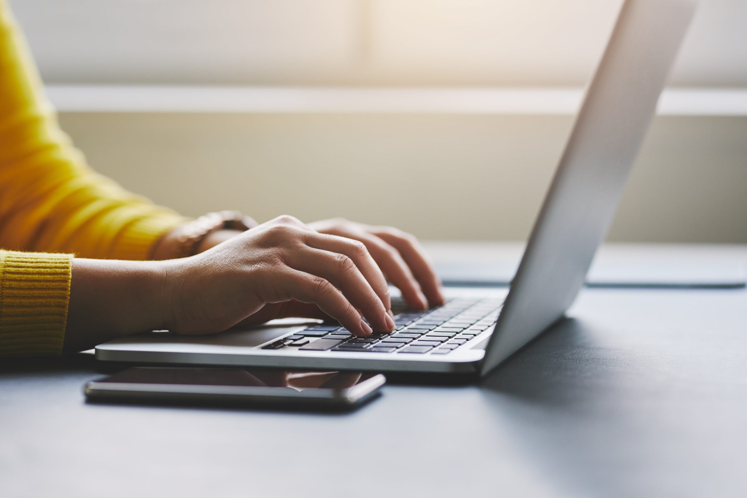 Stock image showing a female typing on a laptop. 